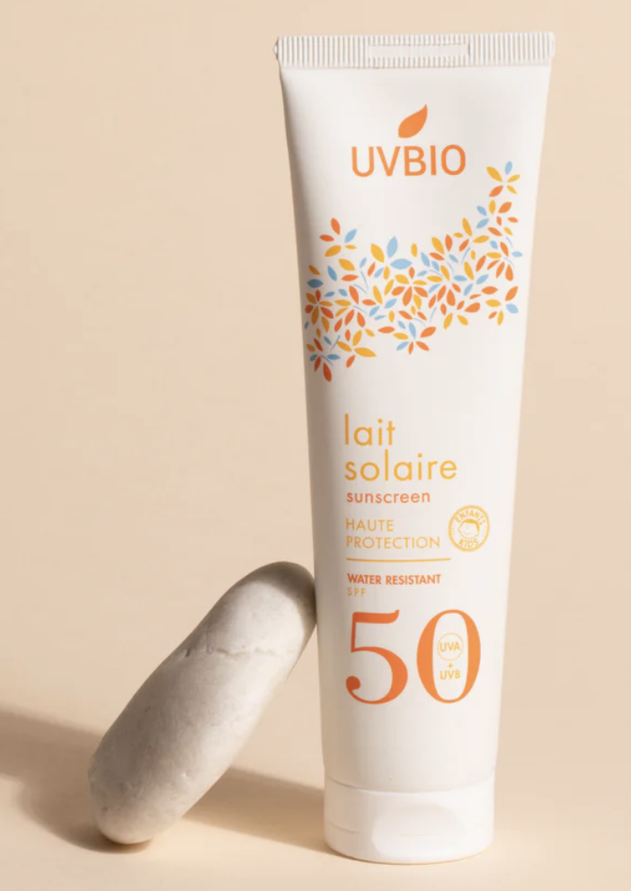 Lait solaire enfant SPF 50 UVBIO haute protection UVA/UVB. Crème solaire bio résistante à l'eau, formule naturelle présentée avec un galet.