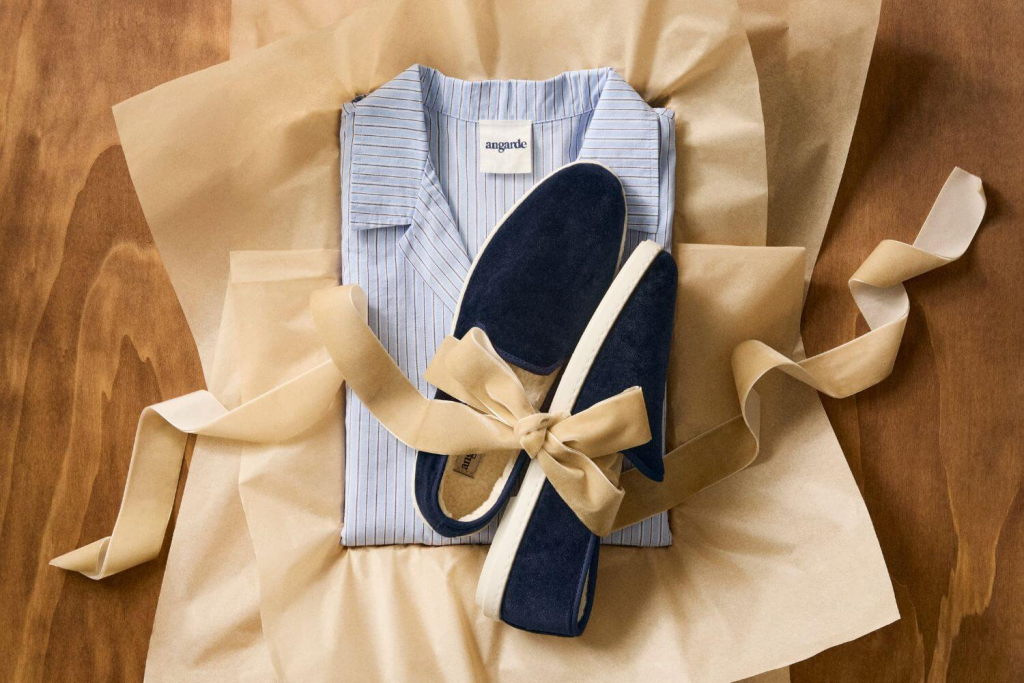 Coffret cadeau mode avec chemise bleu clair à rayures pour femme et chaussons bleu marine, soigneusement emballés dans du papier kraft avec ruban beige, idée cadeau élégante et cosy